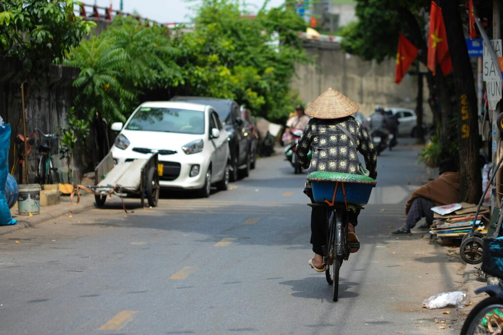 Lifestyle & Culture Woman on bicycle in Vietnamese street with conical hat, vibrant urban life.